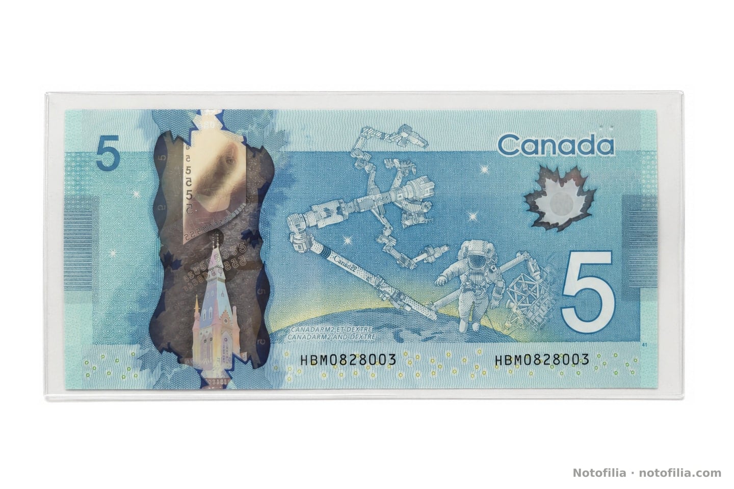 Reverse of the $5: Canadarm2, Dextre, an astronaut, the clear window, and both HBM0828003 serials.
