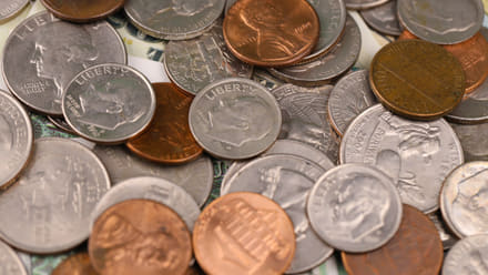 A pile of circulated U.S. coins, including a 2004 Wisconsin quarter, Roosevelt dimes, and Lincoln cents