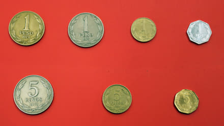 Chilean 1- and 5-peso coins from different periods, obverses and reverses on a neutral ground