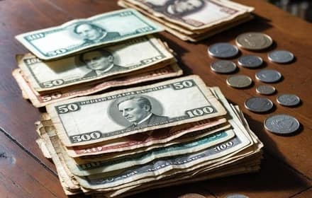 Old banknotes stacked beside collectible coins arranged on a wooden table