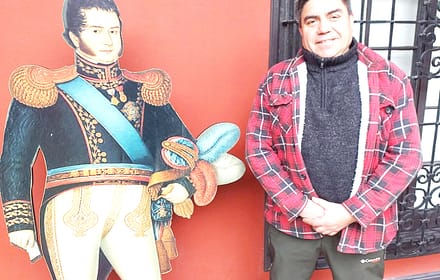 Visitor beside a life-size Bernardo O’Higgins figure in front of a red wall