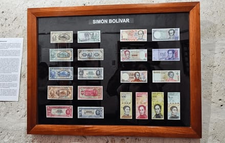 A case of historic notes under a Simón Bolívar label at a numismatic exhibition in Arequipa