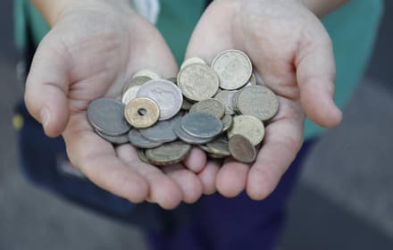 Hands holding a group of old Spanish coins of different periods and metals, including pesetas with the arms of Spain
