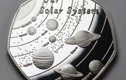 Heptagonal silver medal with the Solar System, orbits, and labeled planets on a gray ground