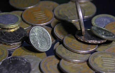Close-up of stacked old Chilean coins with metallic shine on a dark ground