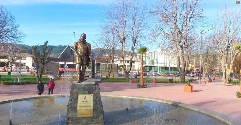 Plaza Alonso de Ercilla en Penco, con árboles, bancas y el escenario al fondo