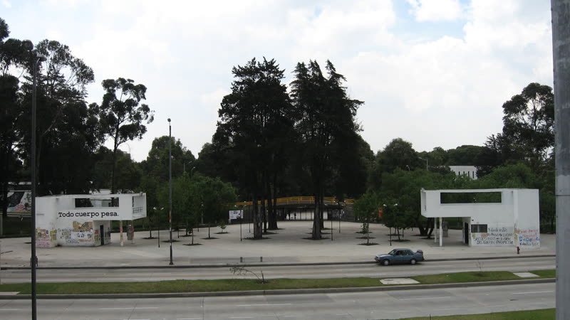 Acceso de la Ciudad Universitaria a la carrera 30 en Bogotá, con árboles y el campus al fondo